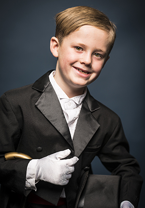 Porträttfoto i studio på Leo Hallman Skäre. En pojke klädd i frack och vita handskar.