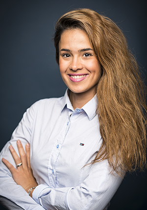 Porträttfoto på Minna Hajilou i ljusblå skjorta med armarna i kors leendes mot kameran.