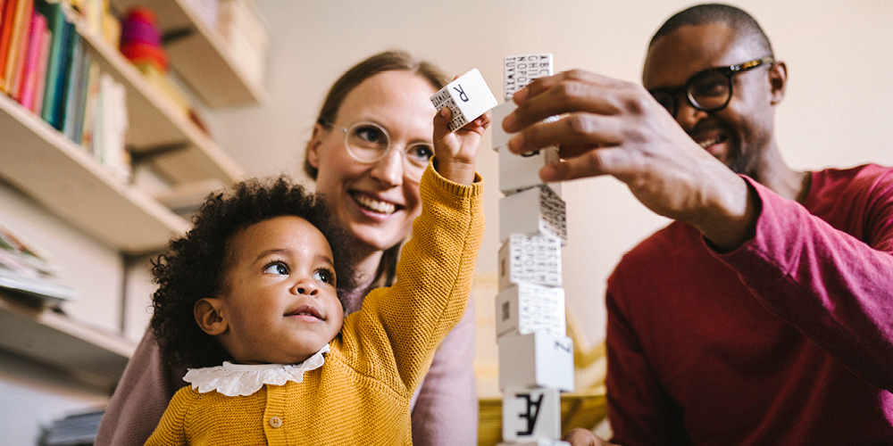 En barnfamilj på tre staplar klossar på höjden.