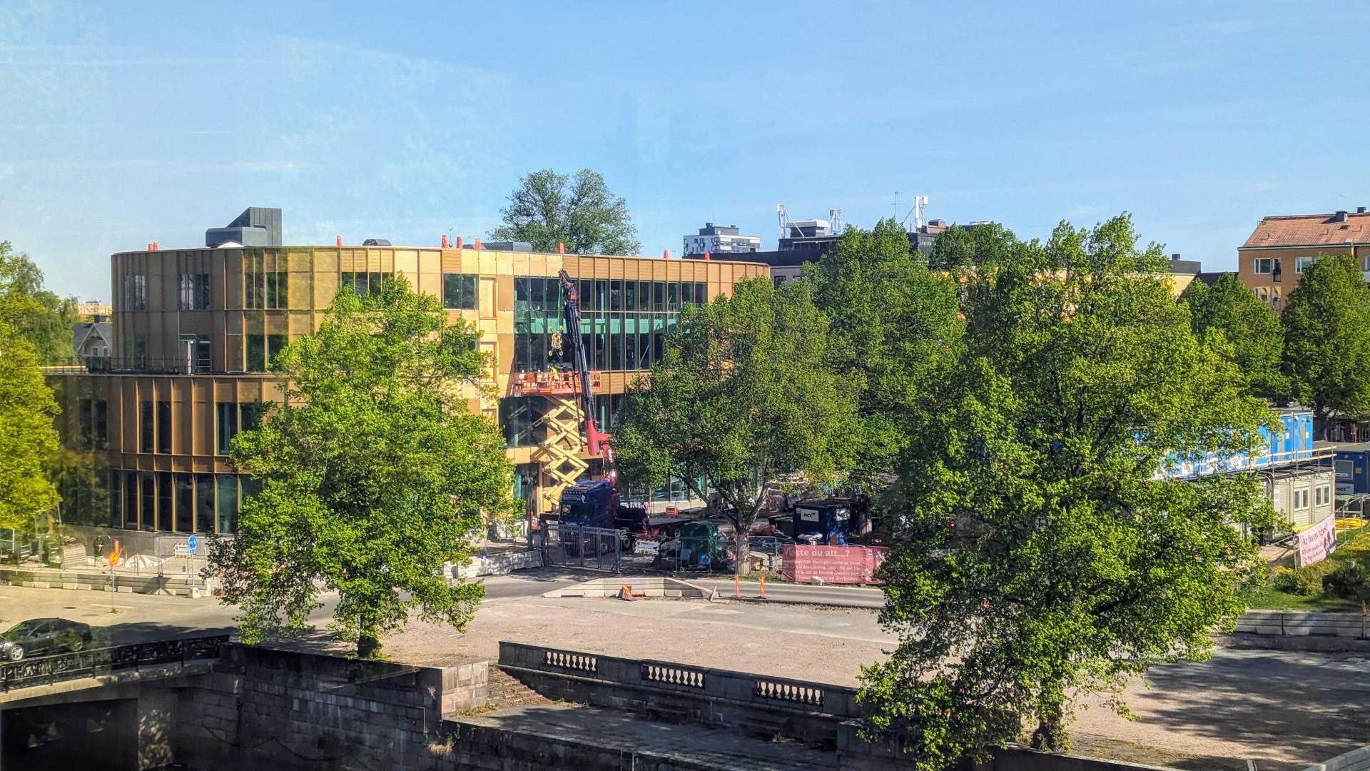 Bilden är på Agnes Kulturhus guldfasad. Huset är omringat av grönska och himlen är blå.