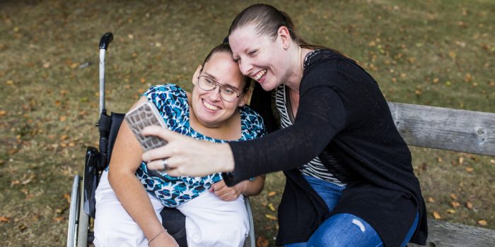 En person i rullstol poserar tillsammans med en medarbetare för en selfie.