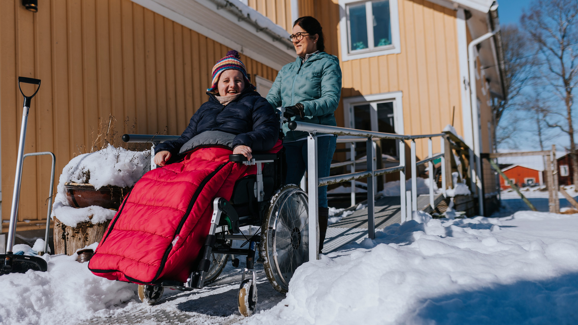 Kvinna som hjälper annan kvinna i rullstol ned för ramp